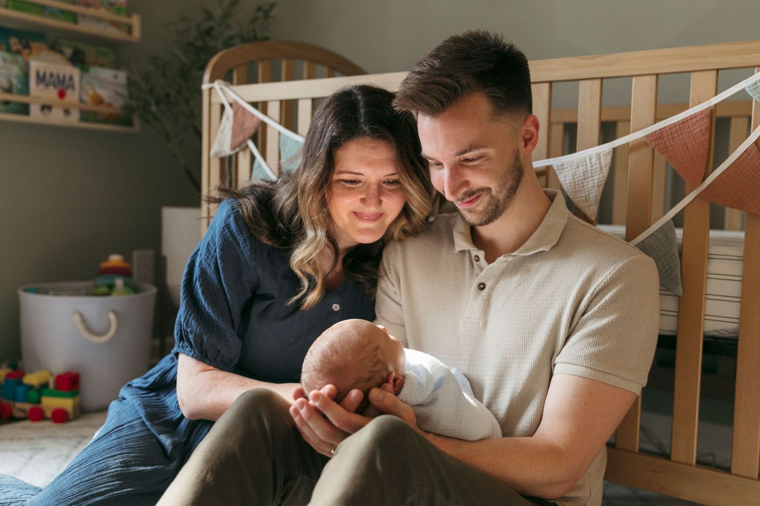Family sharing intimate moments with their newborn in bright, modern nursery setting.