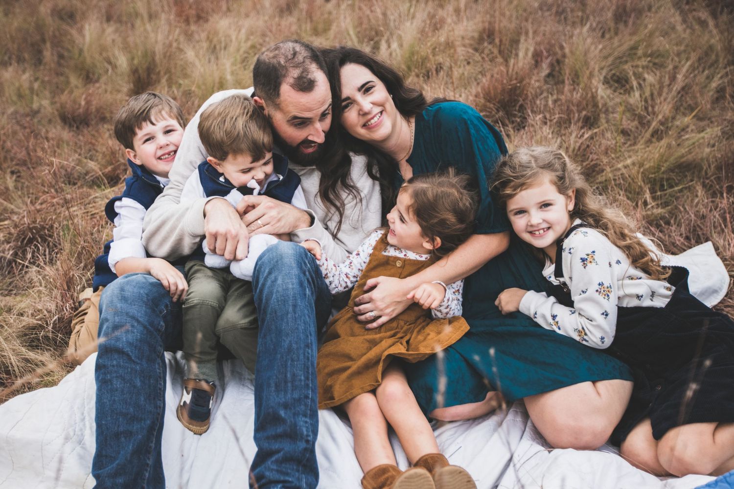 A cozy family gathering on a blanket in a rustic field setting.