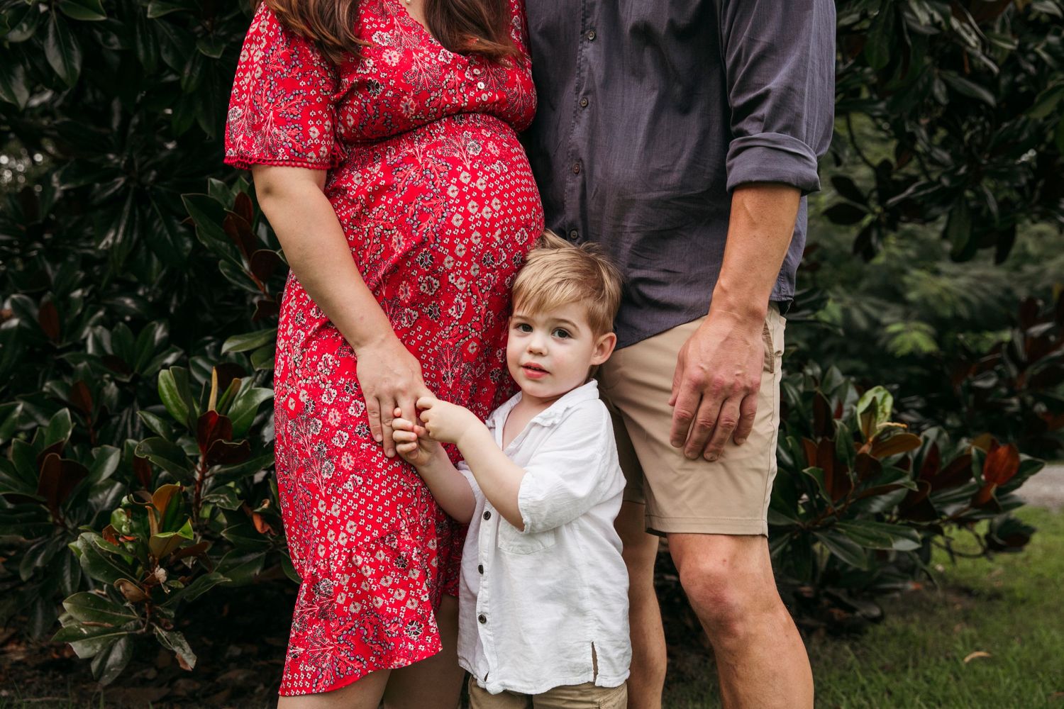 Family in red and white outfits posing together outdoors during portrait session.