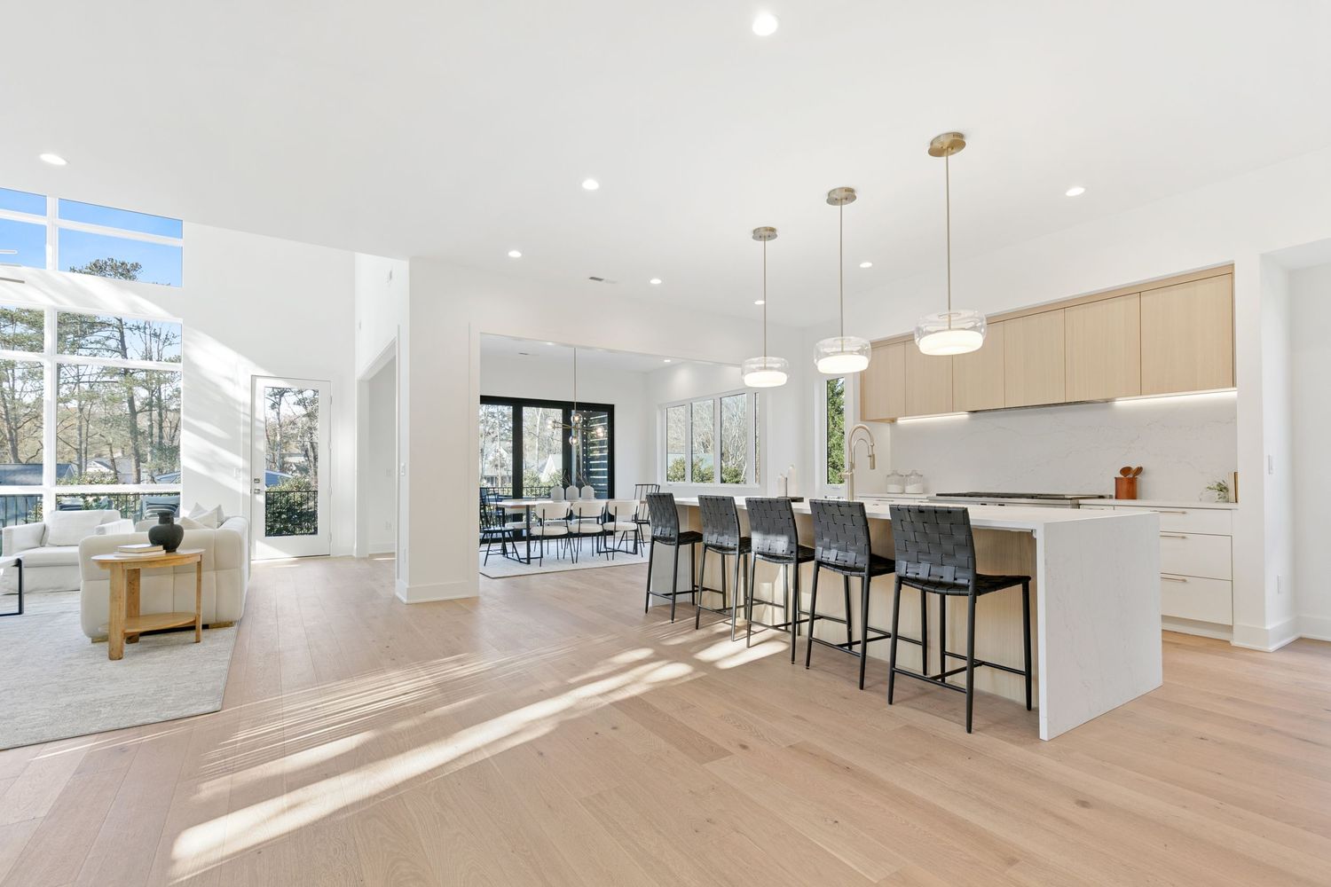 Spacious open-concept kitchen with white counters, wooden cabinets, and floor-to-ceiling windows.