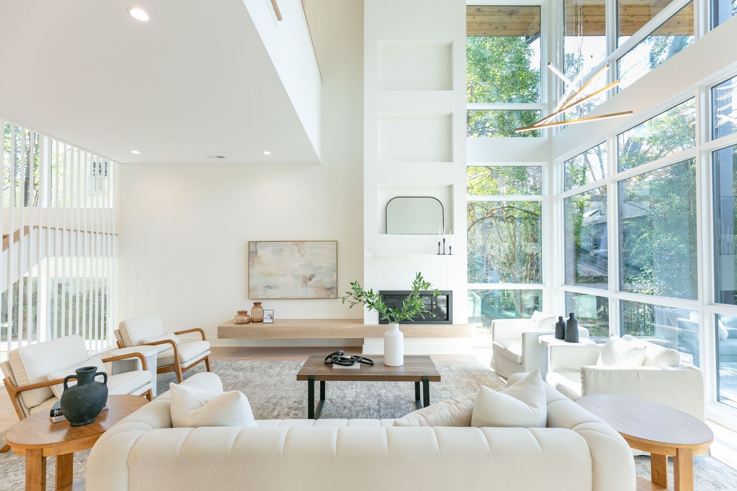 Bright open concept living space with white walls, large windows, and contemporary furniture arrangement.