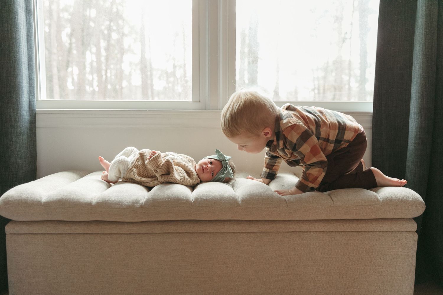A cozy bed with white linens and pillows sits next to a large window with natural light streaming in.