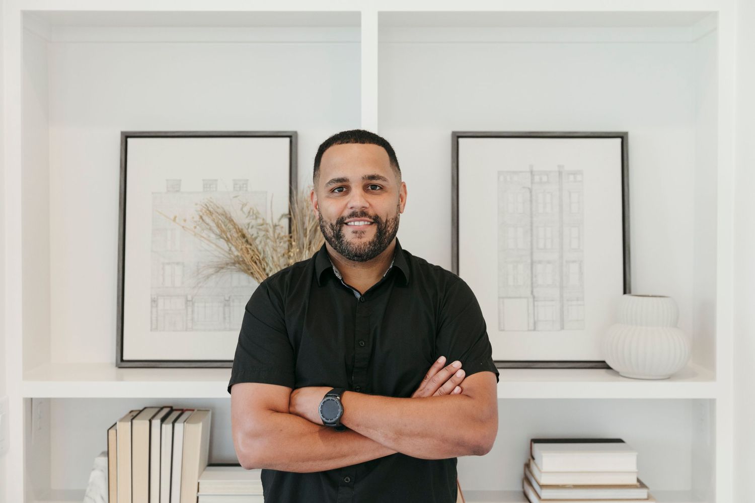 A professional photo in a modern white home office with framed artwork and built-in shelving.