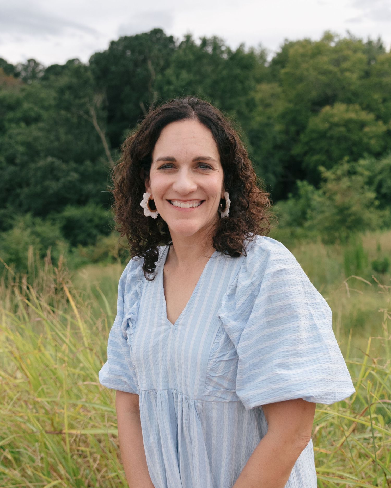 A sequence of natural outdoor portraits showing someone wearing a light blue striped top in a sunny field.