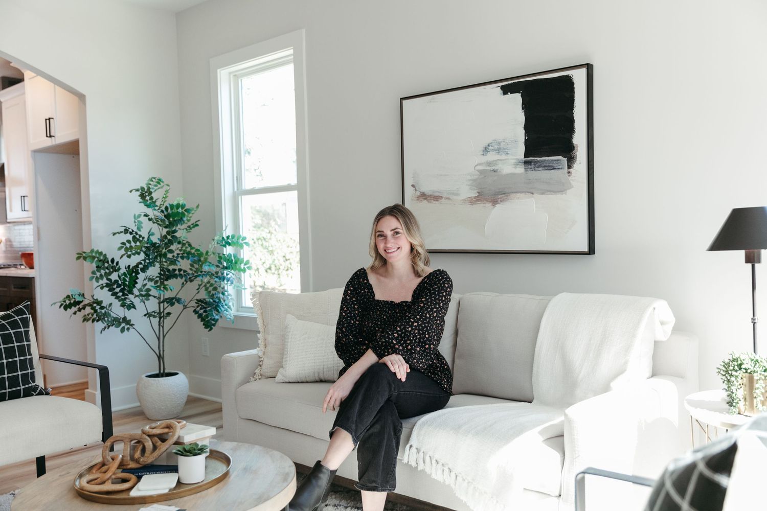 Bright minimalist living room with white sofa, abstract wall art, and indoor plants.