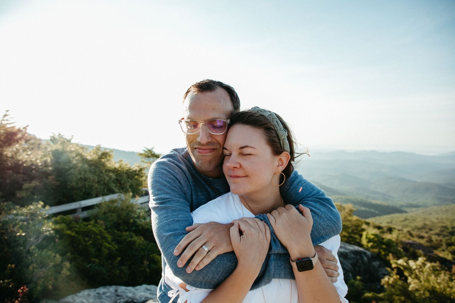 Intimate embrace between couple on mountain overlook during sunset.