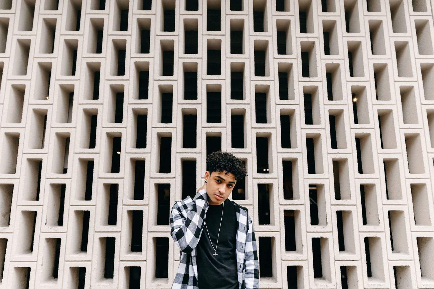 A fashion portrait against a geometric white brick wall pattern.