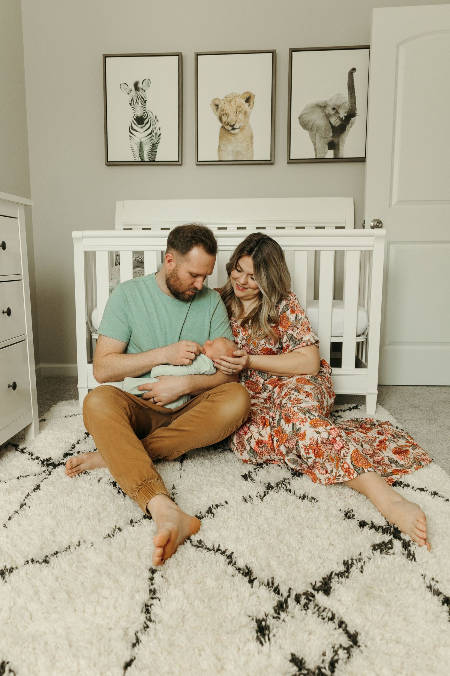 A family gathered on a plush geometric rug in front of animal artwork.