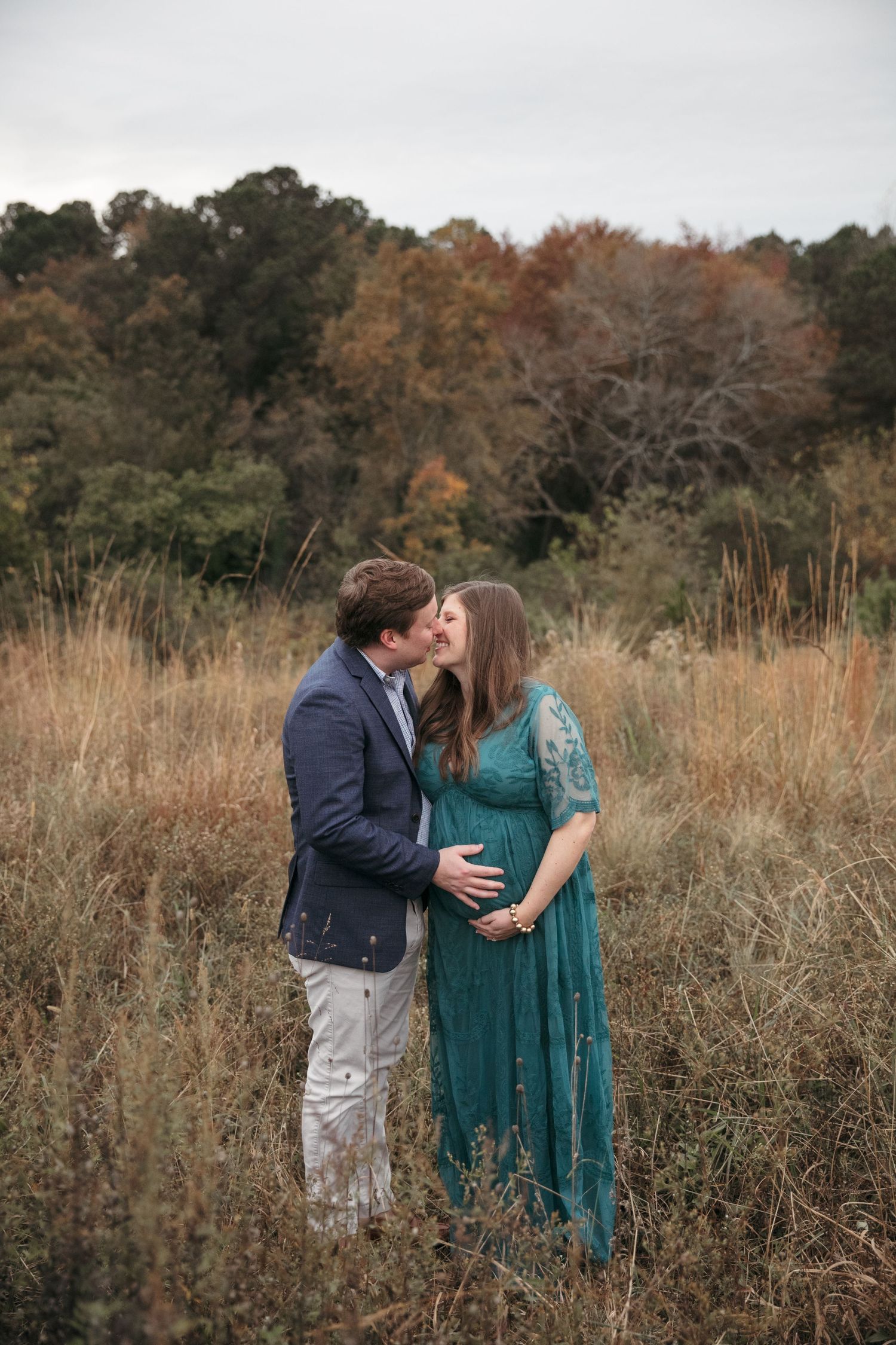 Romantic maternity photo in fall field with couple in formal wear.
