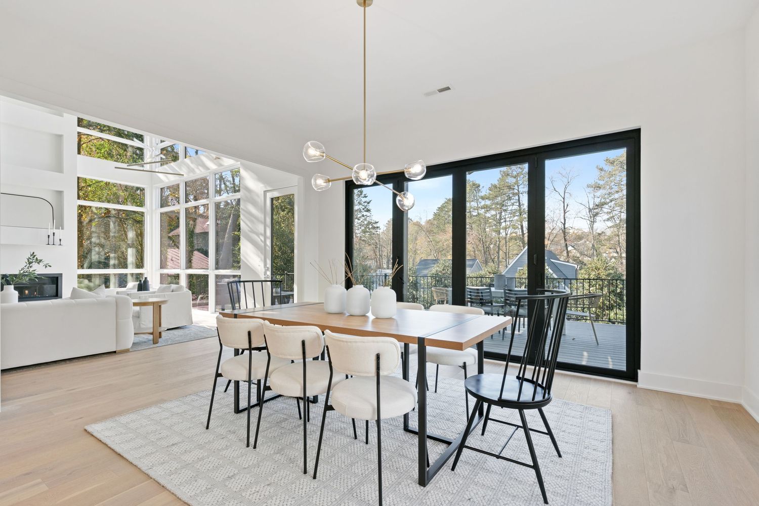 Contemporary dining space with black chairs and pendant lighting, showcasing panoramic windows and bright interiors.