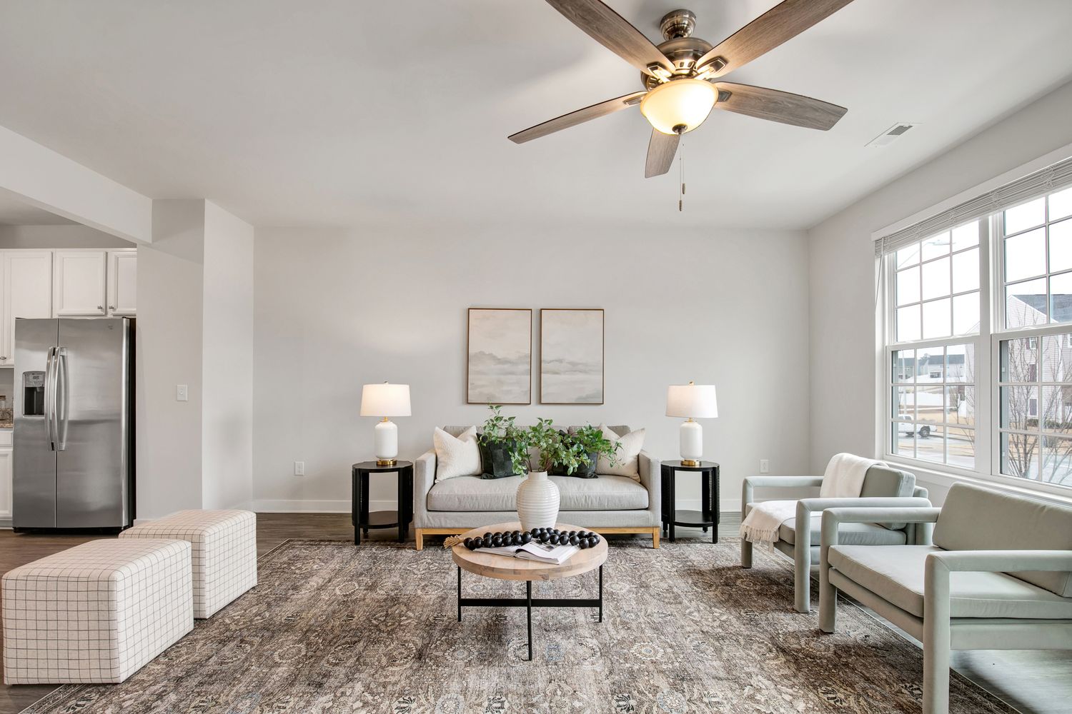 Contemporary living space with gray area rug, modern furniture and ceiling fan in neutral tones.
