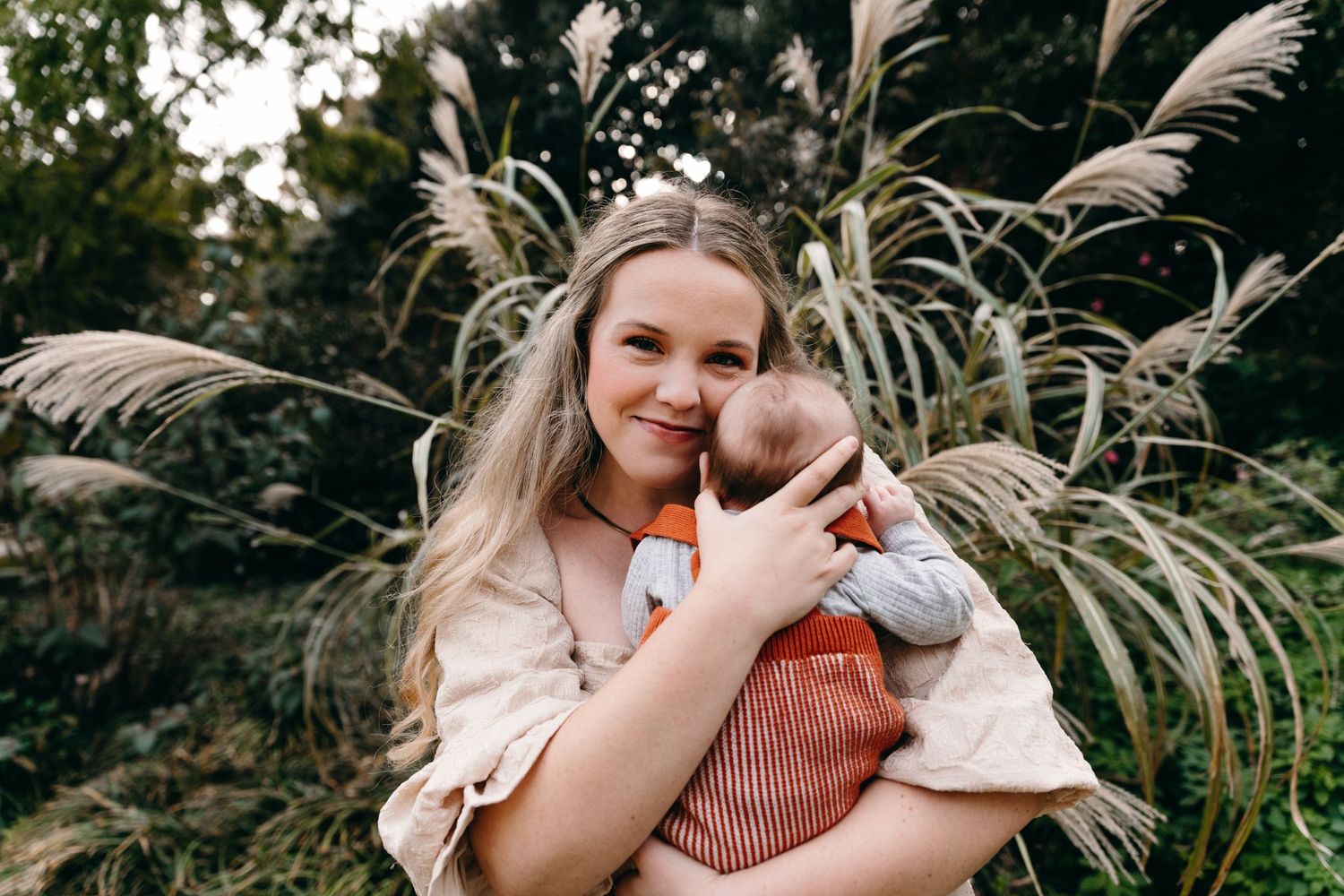 A tender moment captured outdoors with decorative pampas grass in the background.