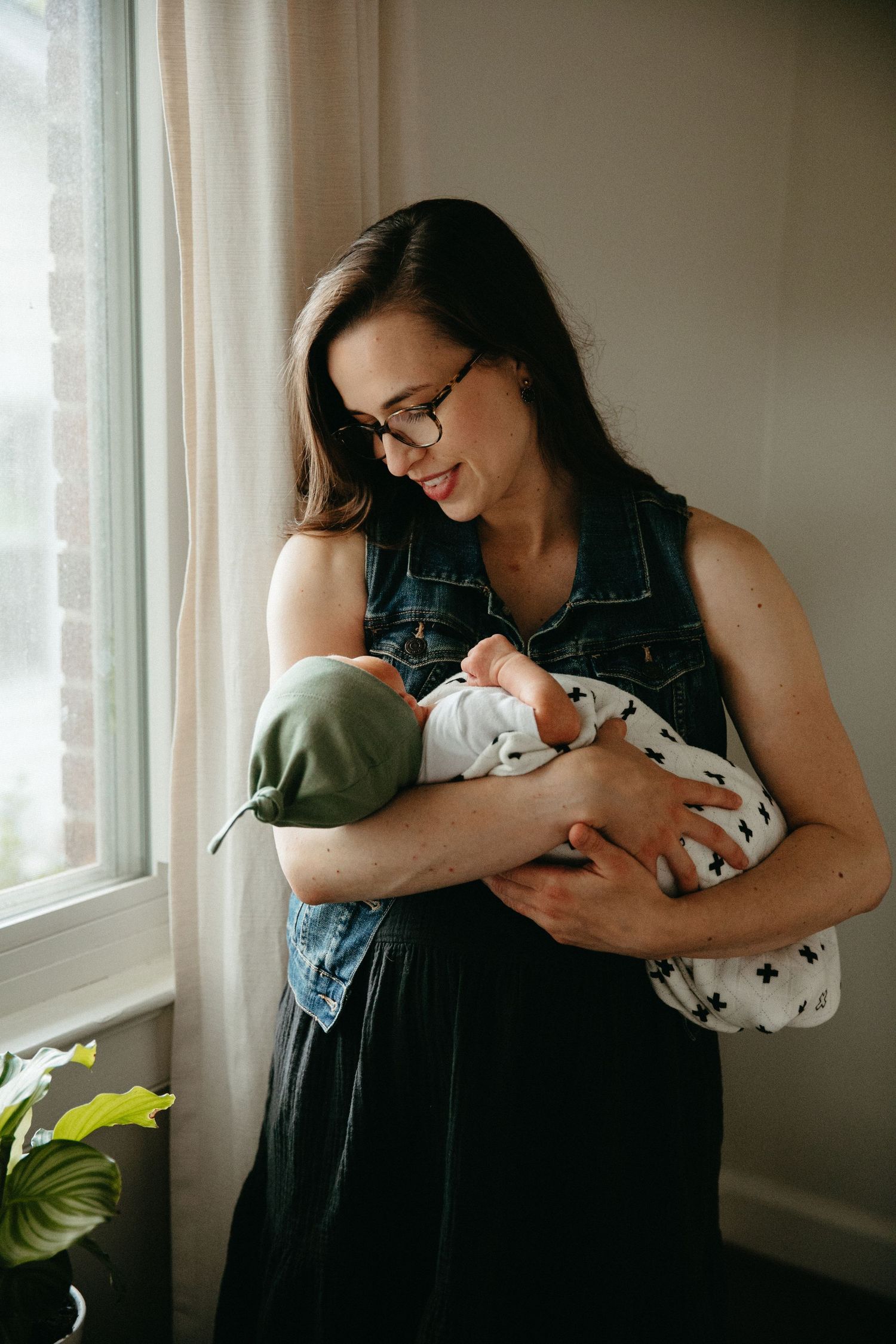 Natural window light illuminates tender moments with a newborn in a cozy home setting.