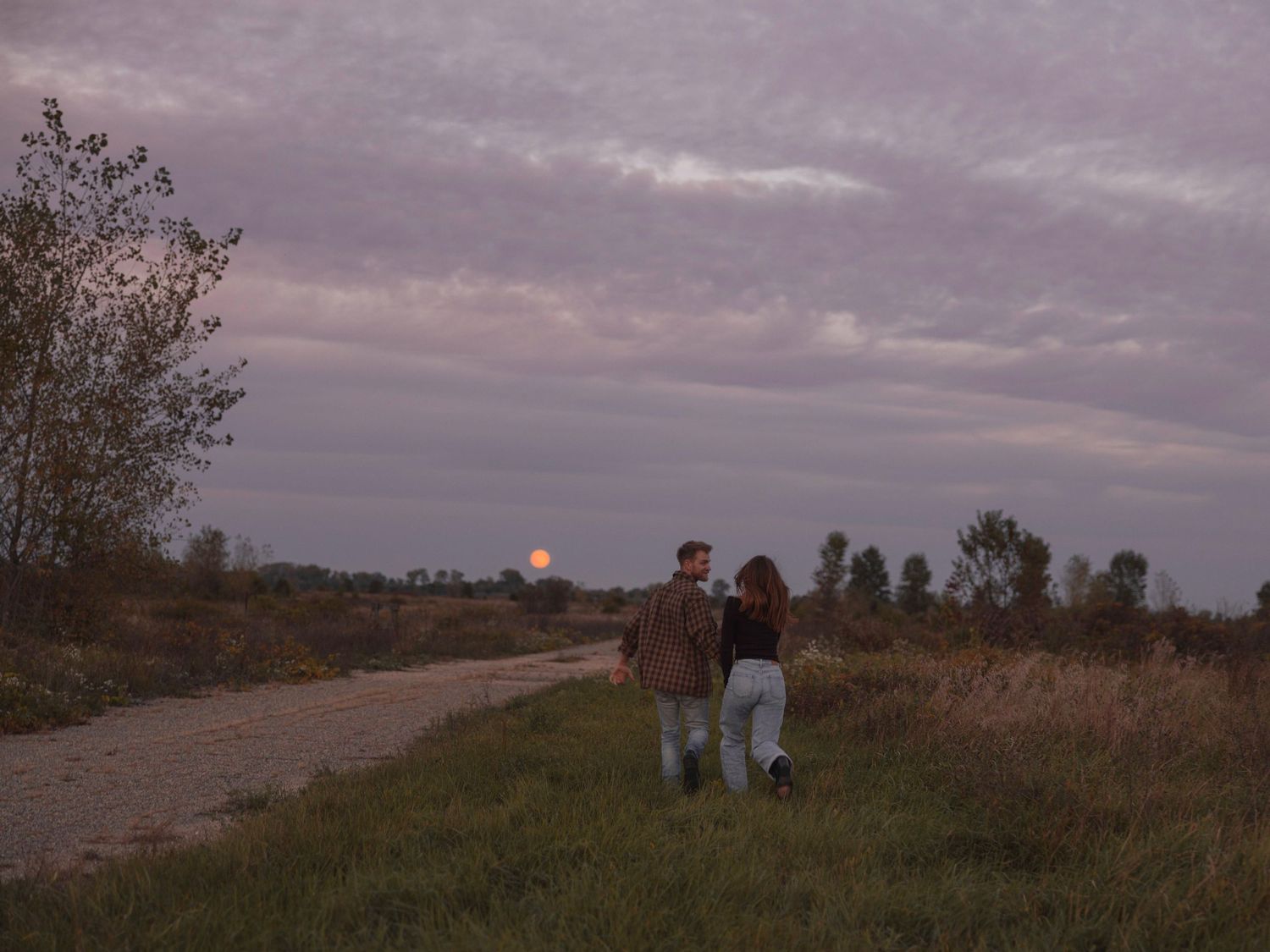 Loving couple standing alone gravel road with the rising moon in the background