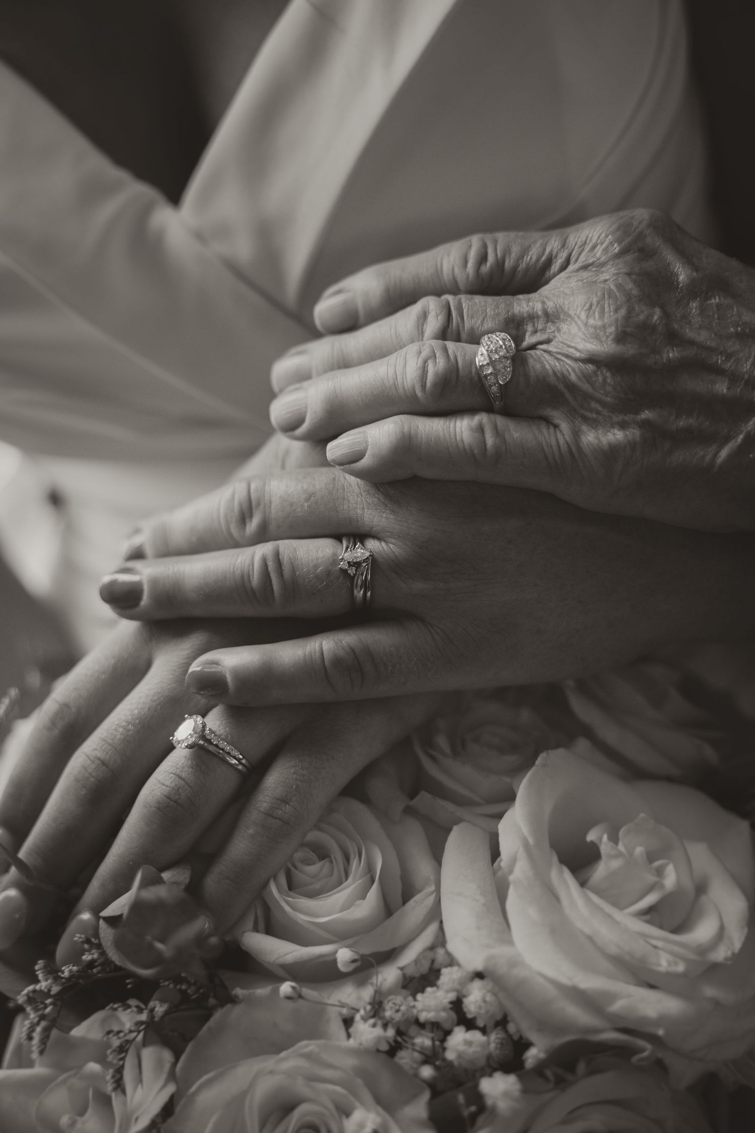 Black and white photo of bride and grandmother's hands over wedding bouquet.