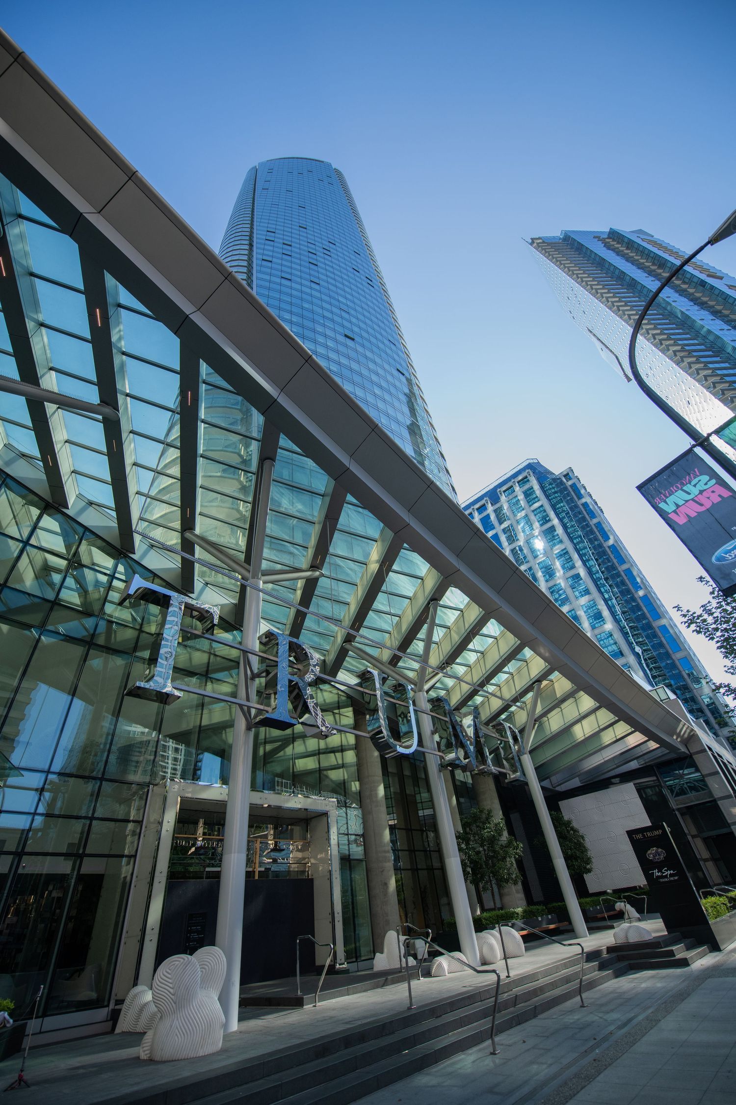 Looking up at the glass entrance of a luxury high-rise Rogue building surrounded by downtown skyscrapers.