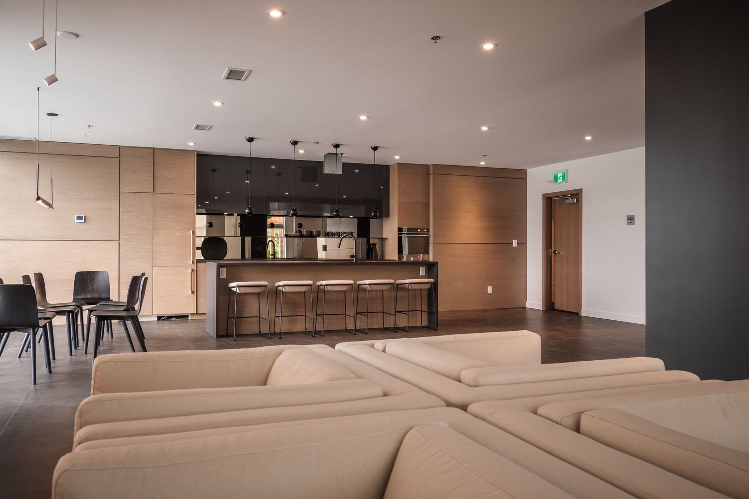 Modern open-plan lounge area with a bar, wood paneling, and neutral-toned furniture.