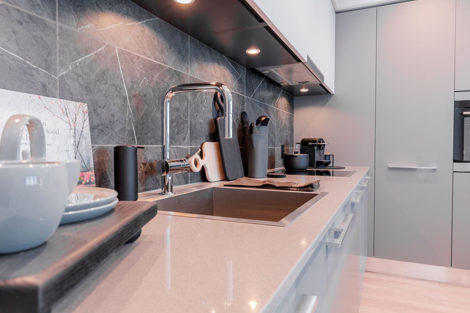 Sleek modern kitchen countertop with marble backsplash, undermount sink, and stainless steel faucet.