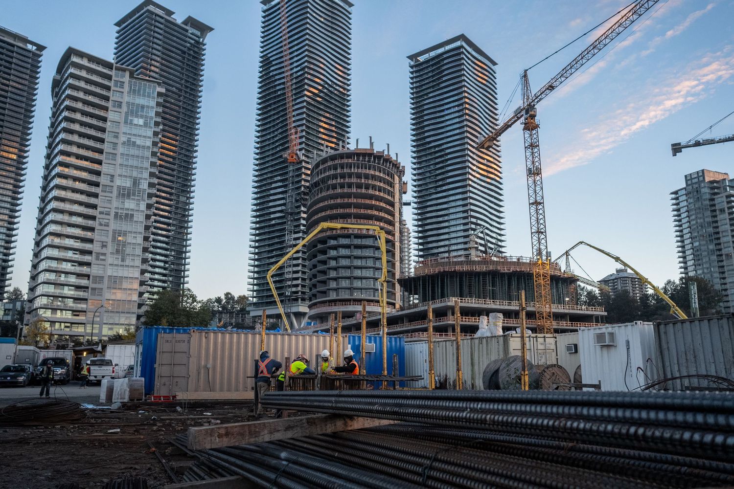 Aerial view of a large urban construction site surrounded by modern high-rise buildings at dusk.
