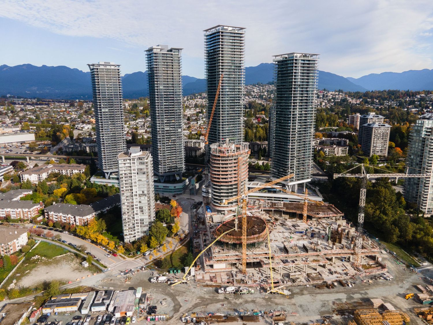 Aerial view of a major construction site with cranes and high-rise towers in a suburban city.
