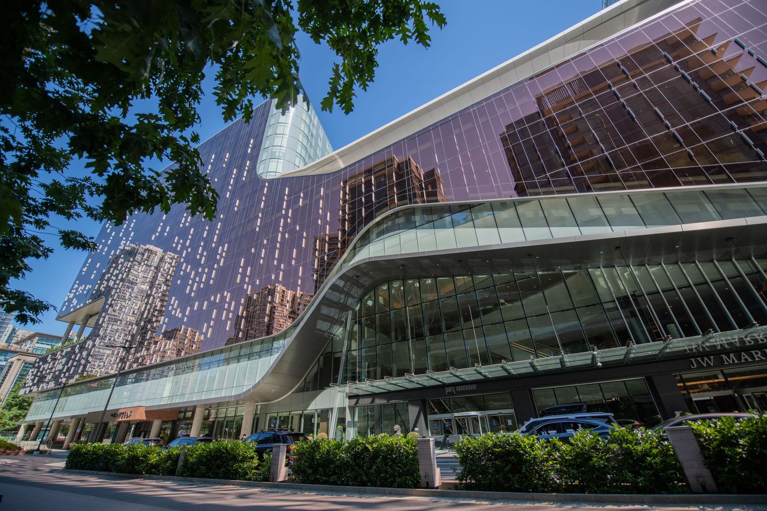 Contemporary glass and steel commercial building with curved architecture reflecting sunlight in an urban downtown setting.