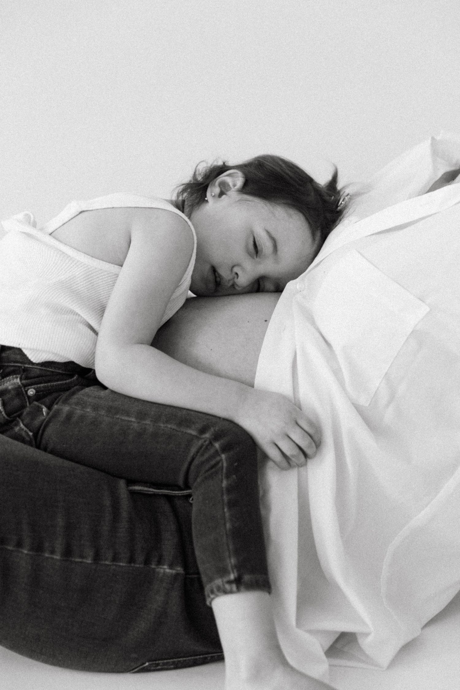 Side view of sleeping figure in white tank top and jeans on white background.