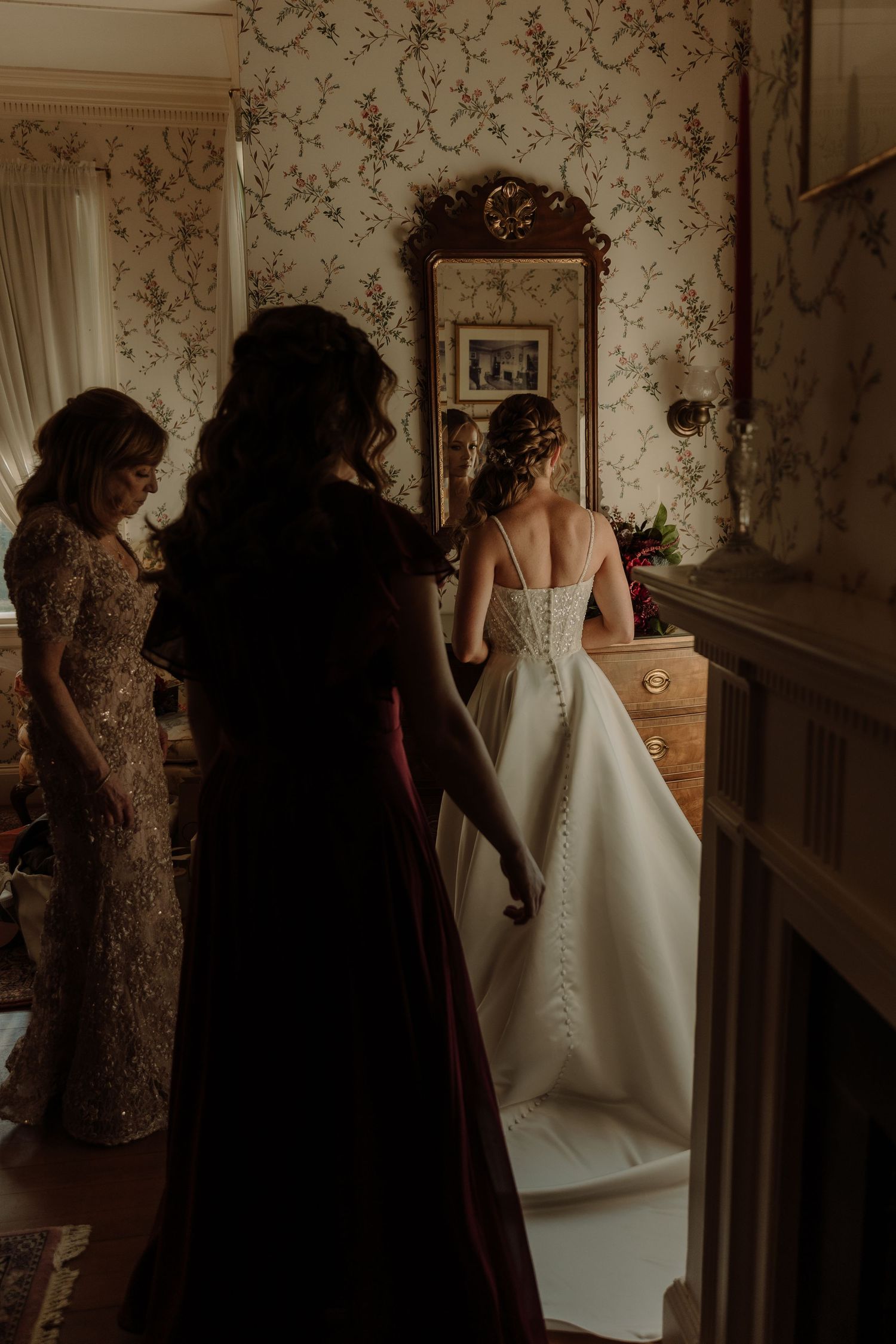 Wedding day preparations showing a bride in a white gown being helped by attendants in a vintage-styled room.