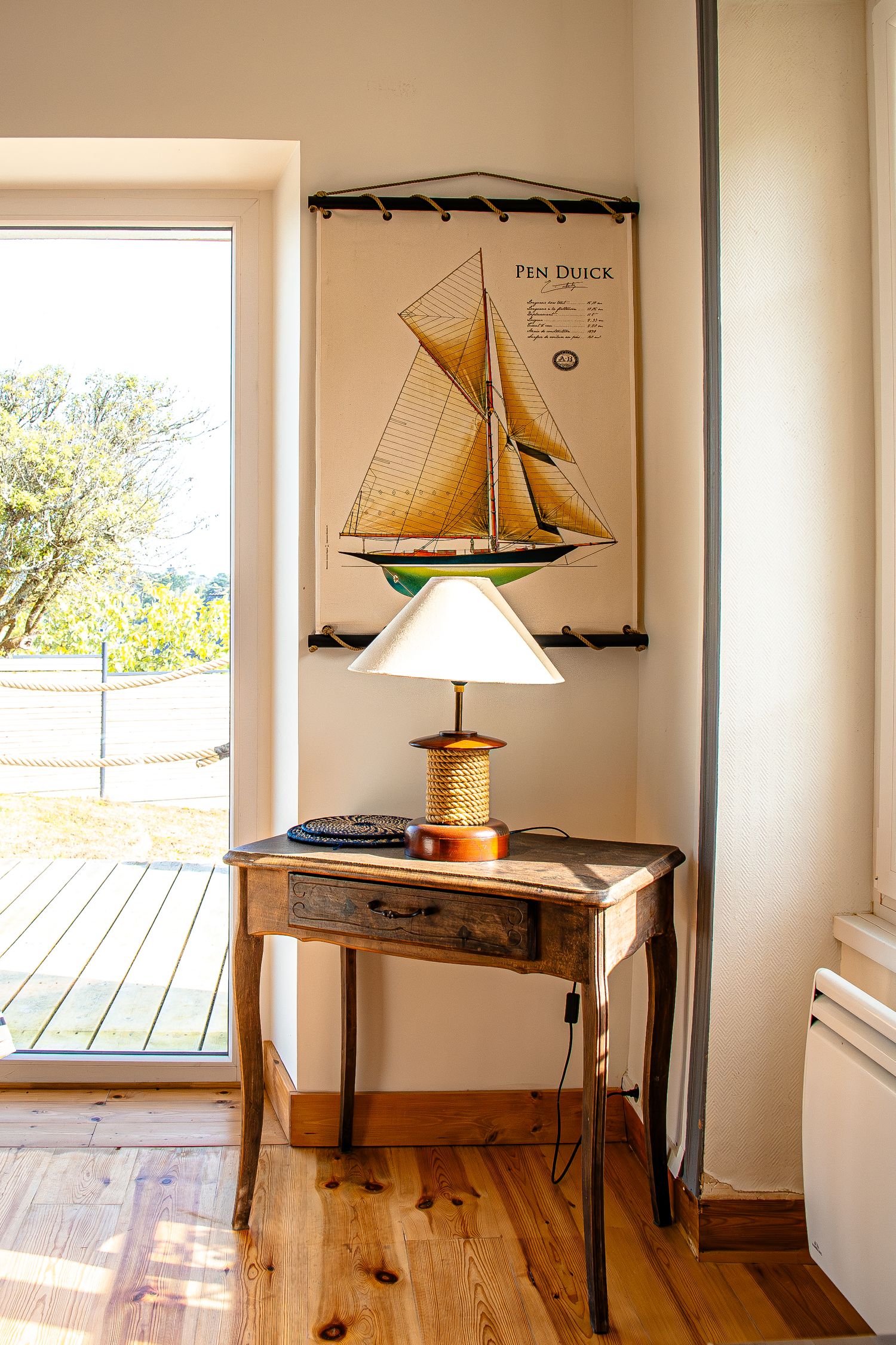A panoramic view of a room with model sailboats and maritime decor displayed on tables against white walls.