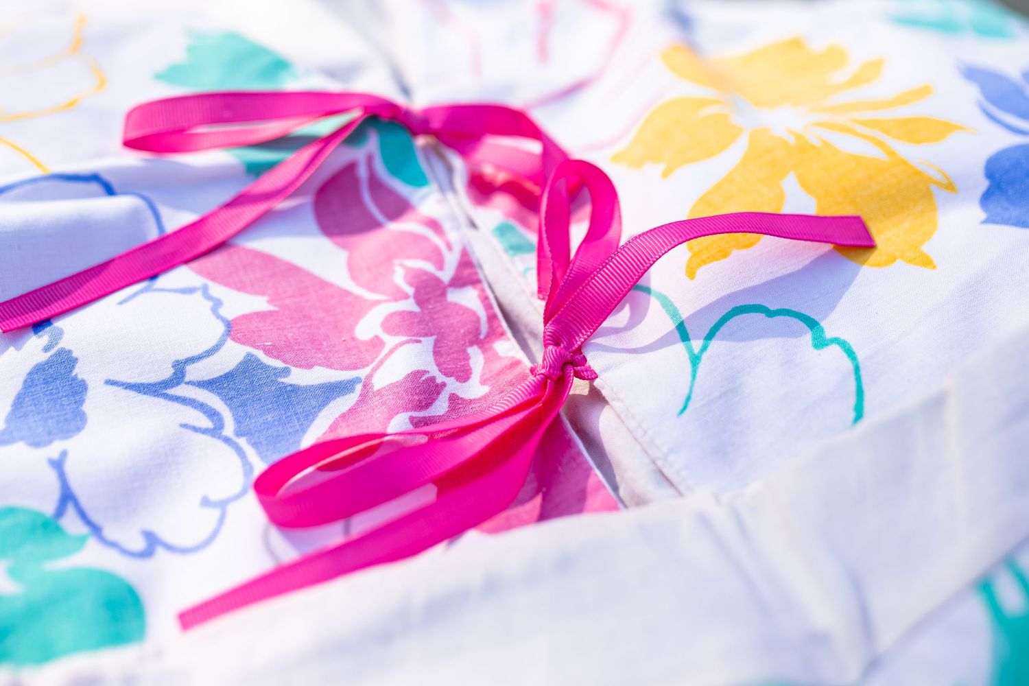 A bright floral pattern fabric with a vibrant pink ribbon bow tied on top.