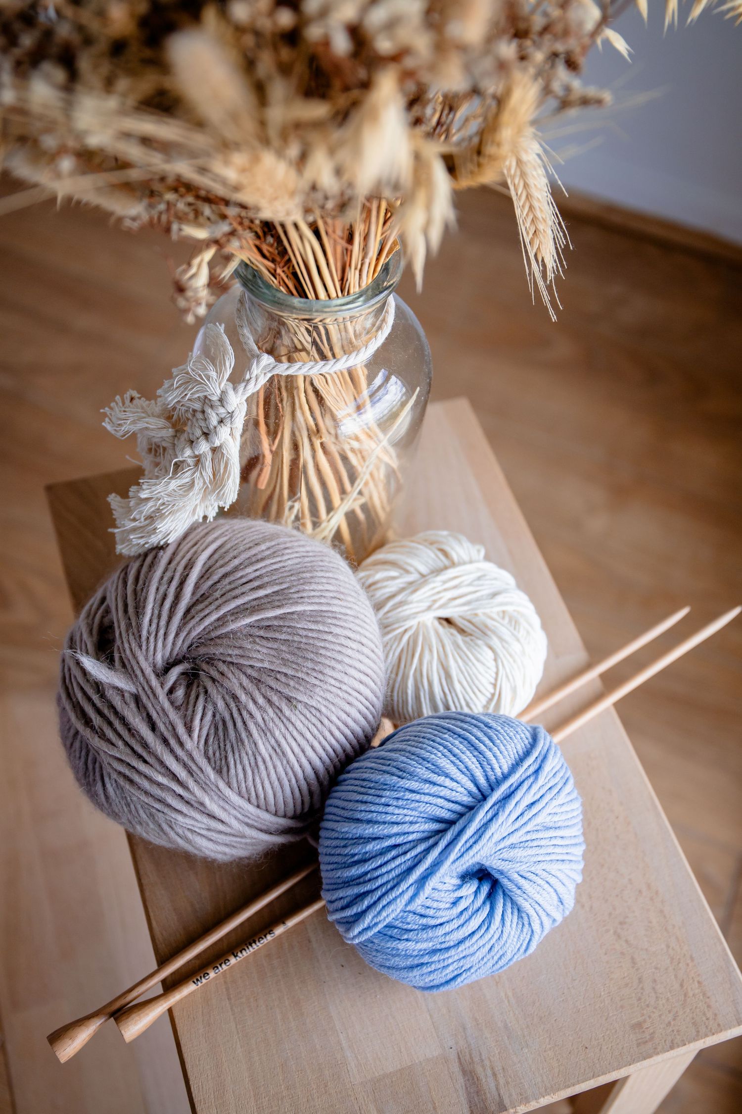 Knitting supplies with blue and gray yarn balls and wooden needles on a table.