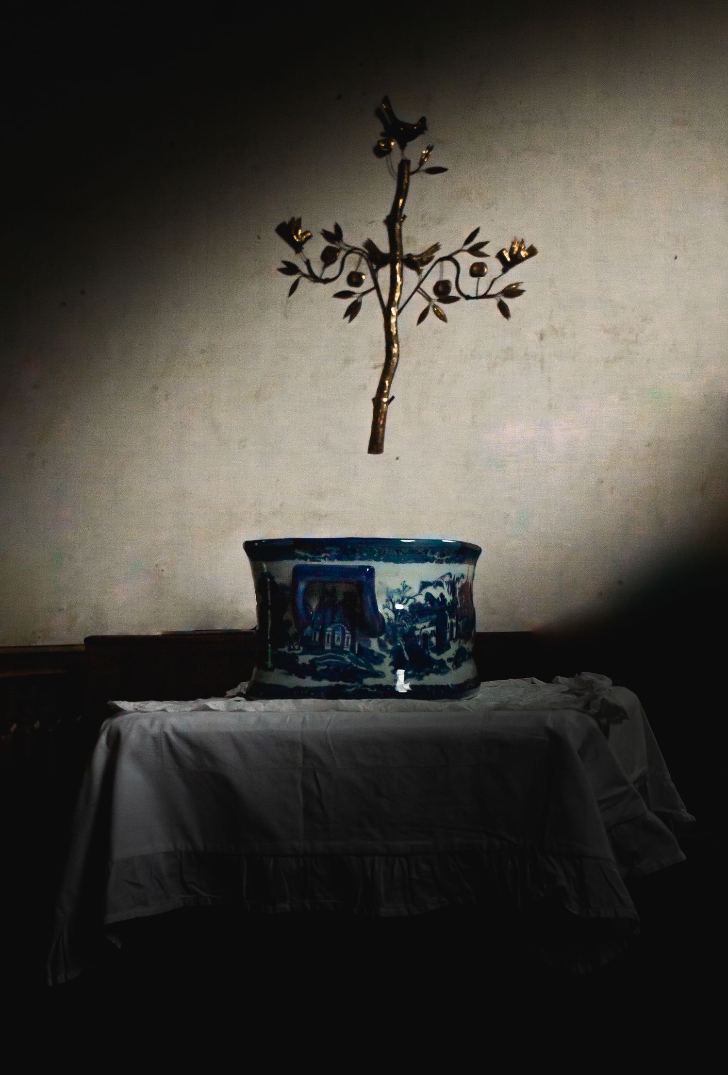 An artistic still life with a blue bowl and cross shadow on a dark table.