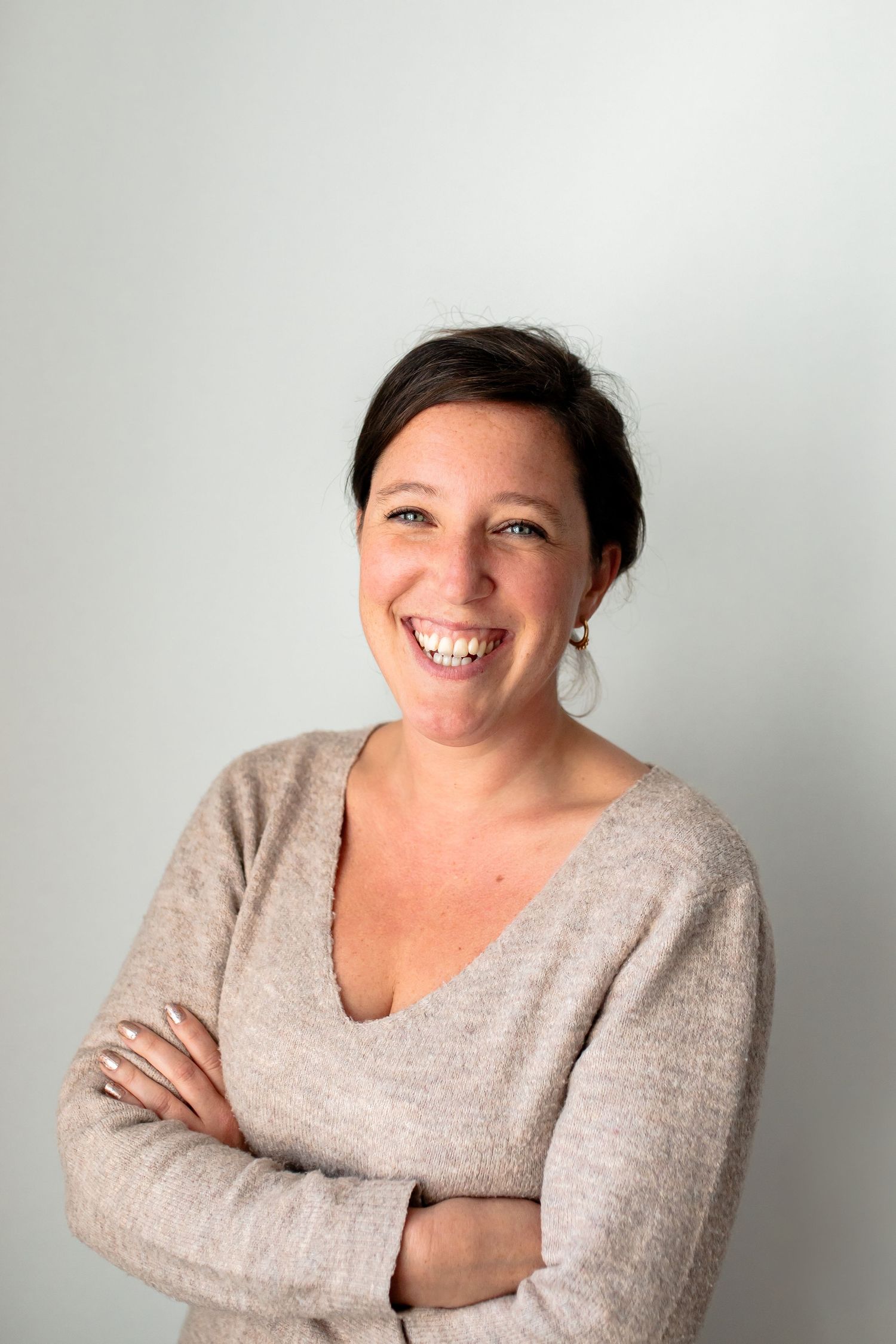 Cheerful portrait of someone in a beige sweater against a light background.