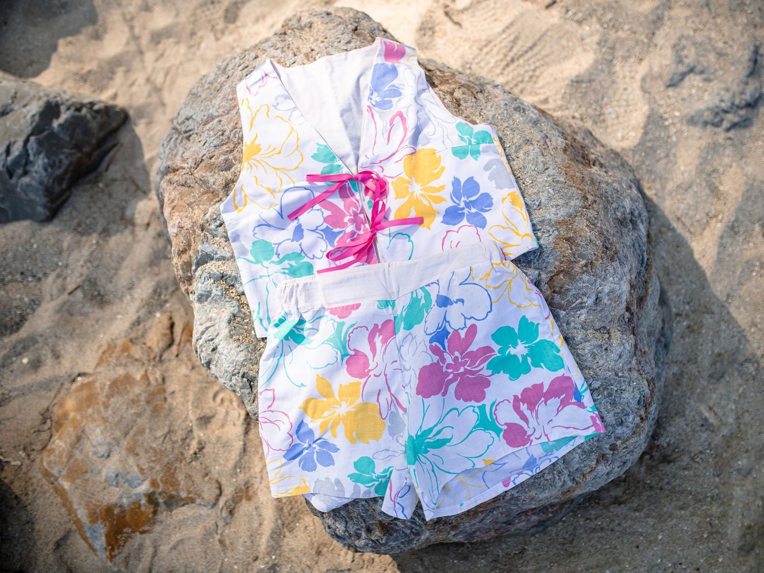Colorful watercolor paintings on paper placed on rough stone or rock surfaces in a natural outdoor setting.