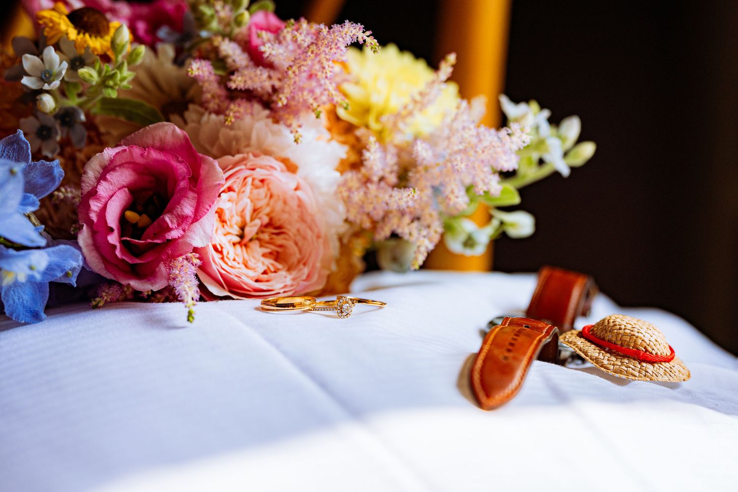 Elegant floral centerpiece with pink roses, orange candles and delicate white flowers on a white tablecloth.