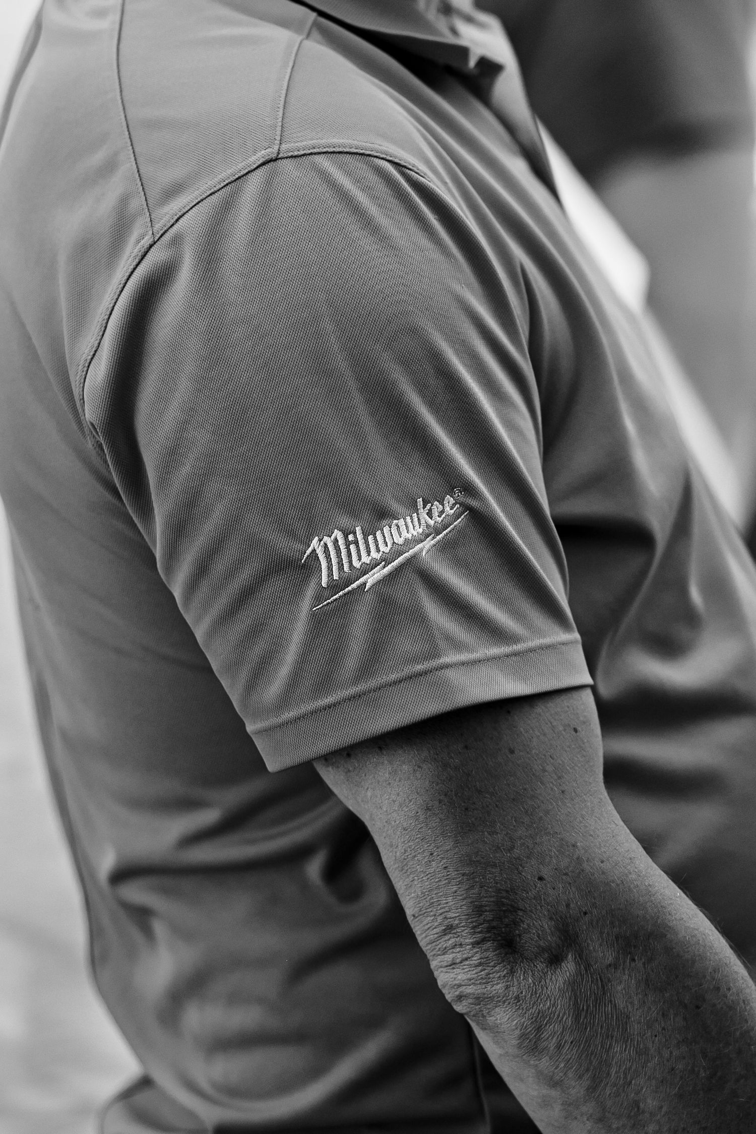 Black and white detail shot of a Milwaukee brand logo on a sleeve of athletic wear.