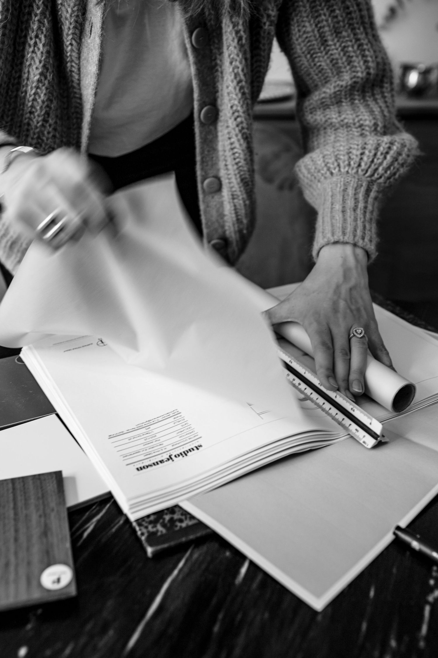 Hands working with papers and documents on a dark wooden surface.