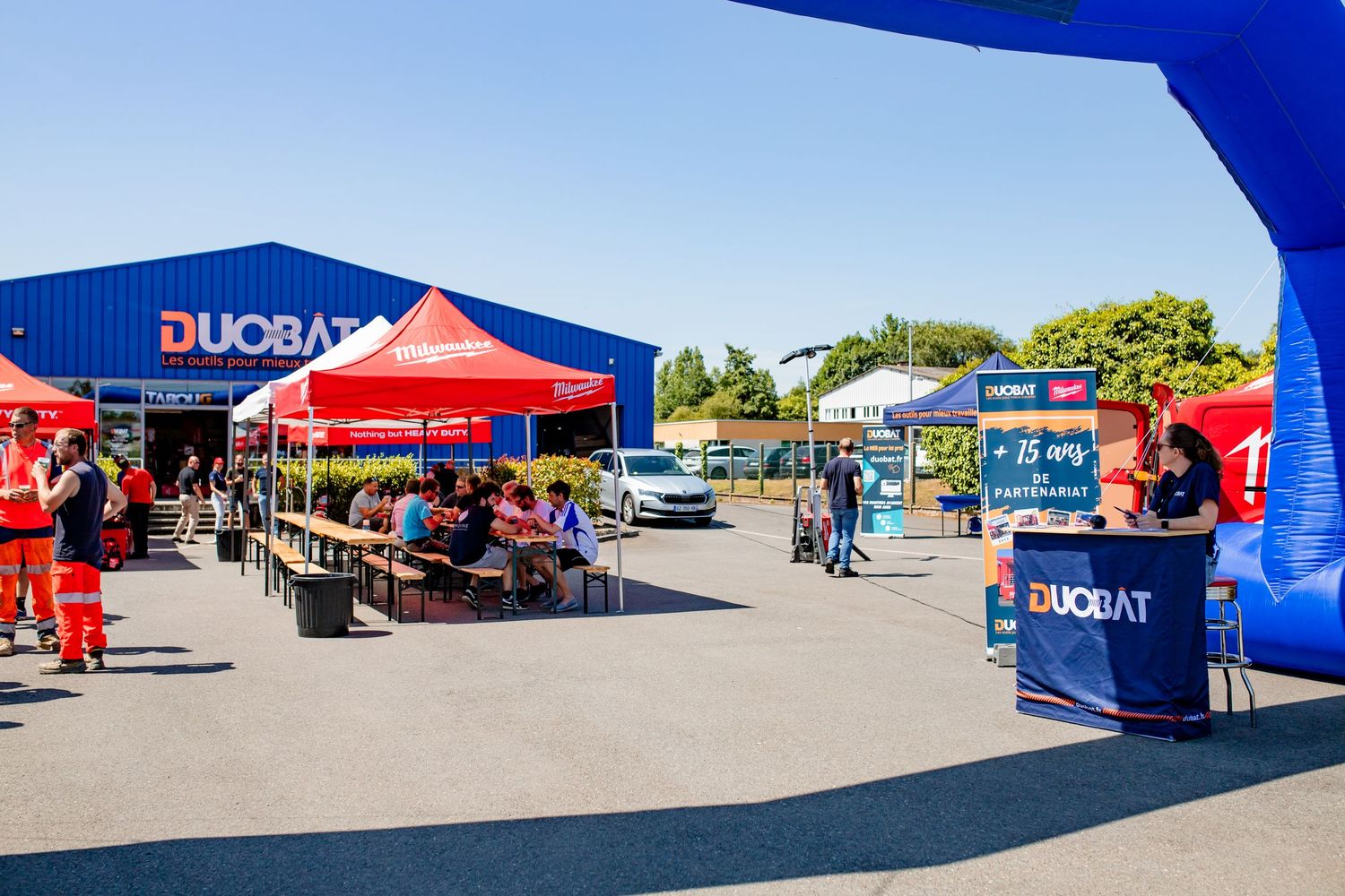 Outdoor event space with blue and red tents set up in a parking lot area.