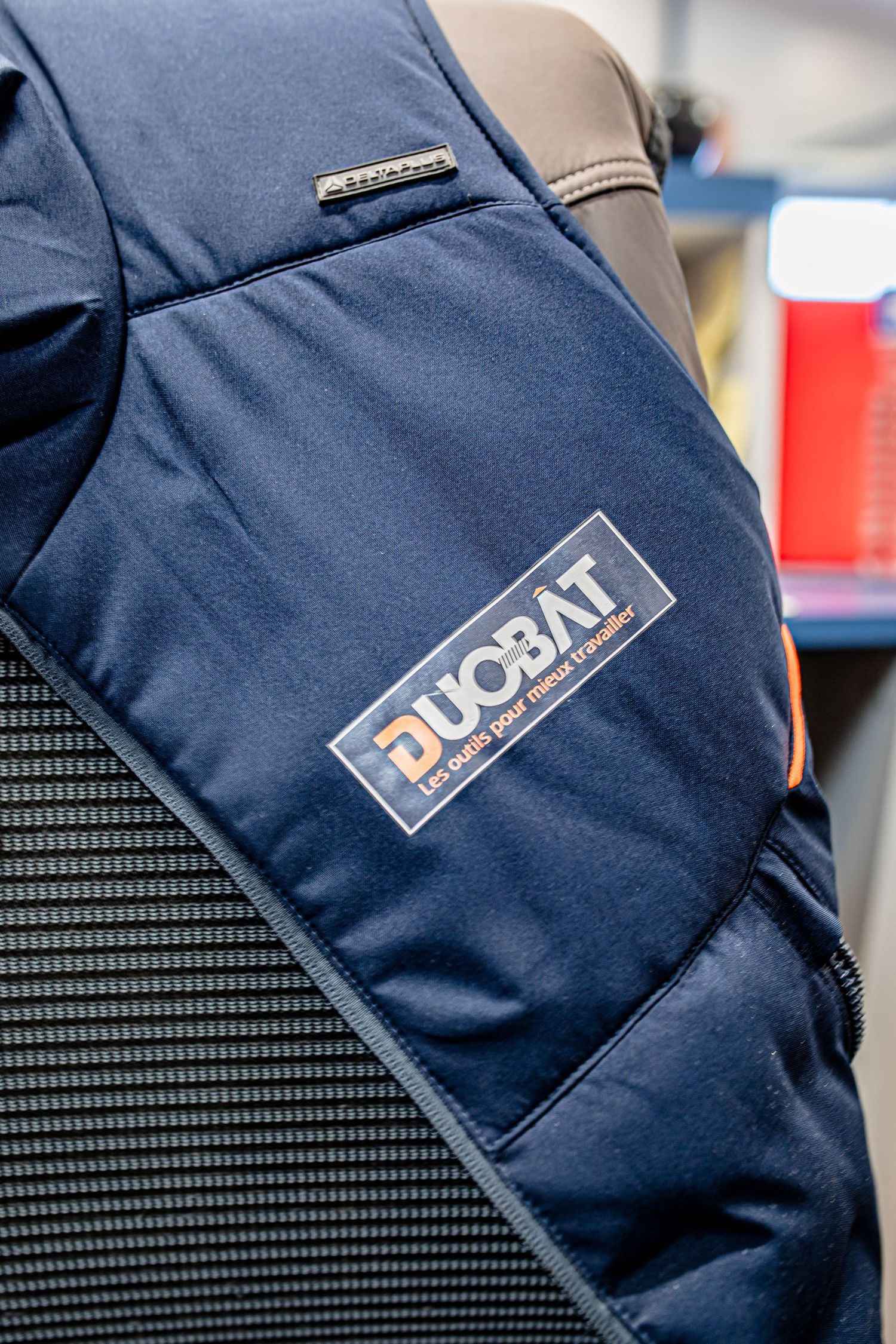 Close-up of a navy blue workwear jacket with Duobat logo patch.