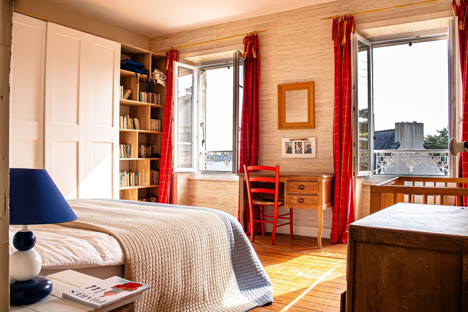 Panoramic view of a cozy wood-paneled apartment interior with red curtains and built-in bookshelves.