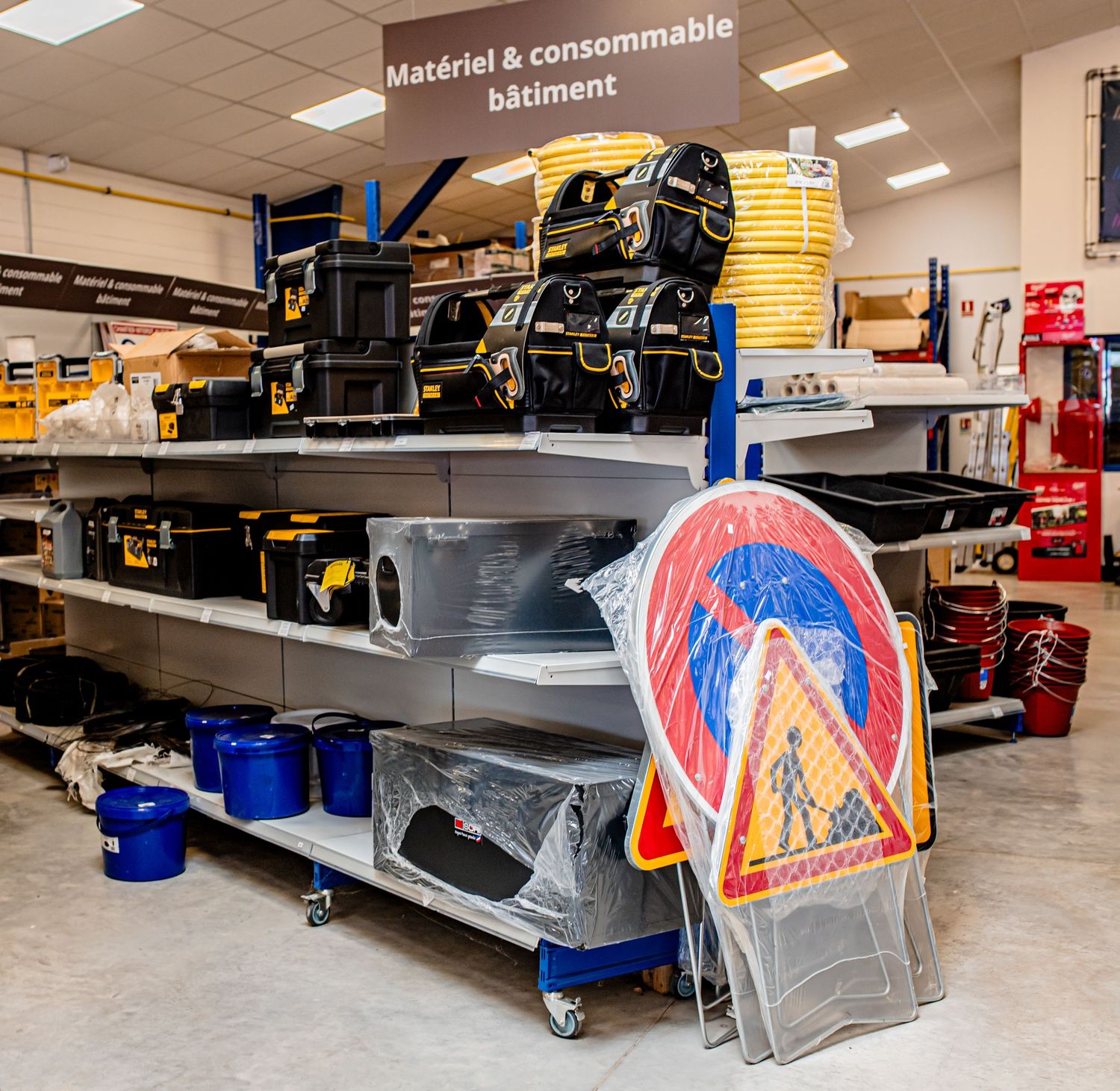 Storage area with maintenance equipment and stacked yellow buckets on industrial shelving.