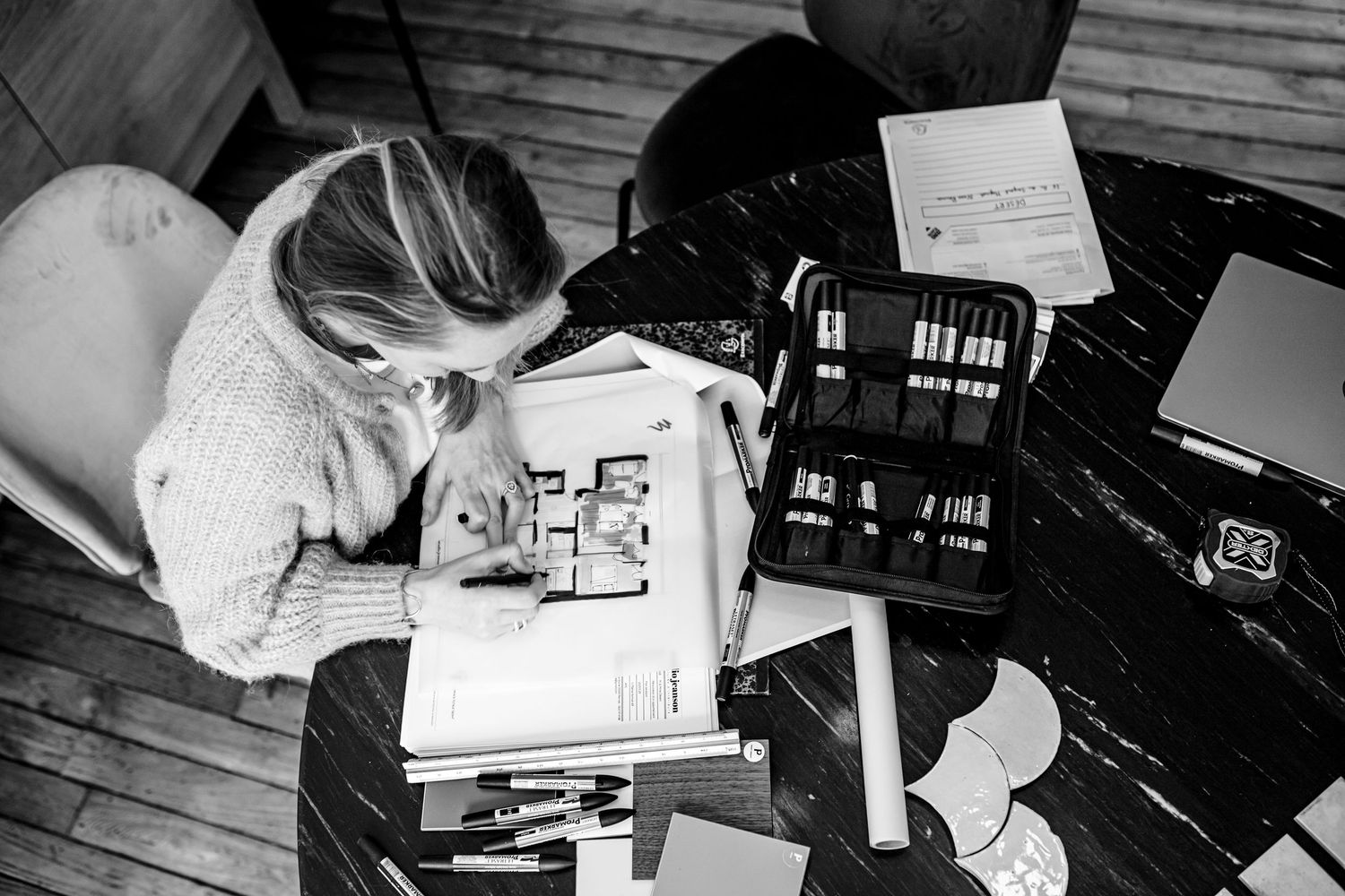Architectural plans and design materials spread across wooden floor.