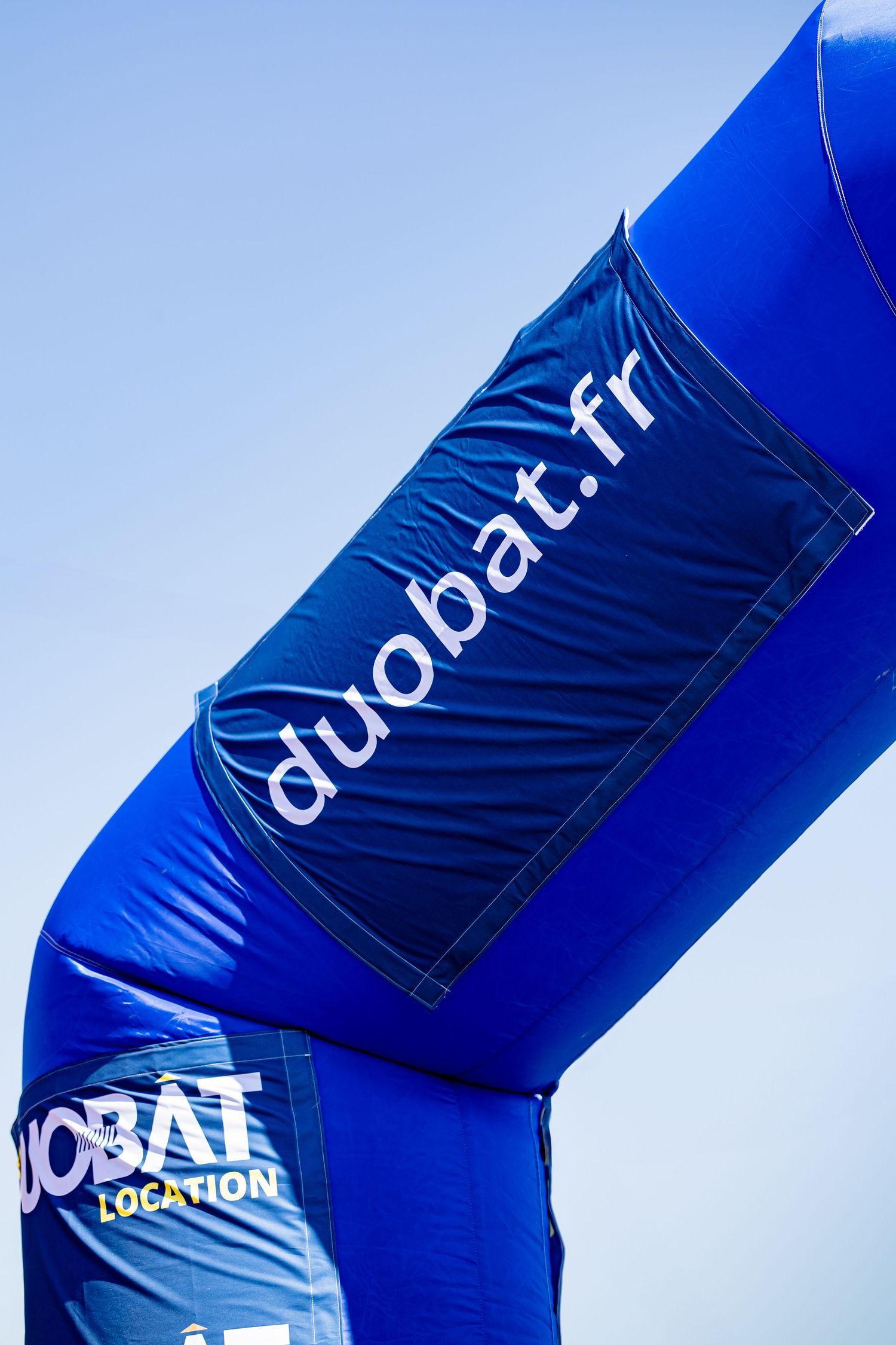 Blue inflatable arch with Duobat.fr branding against sky background.