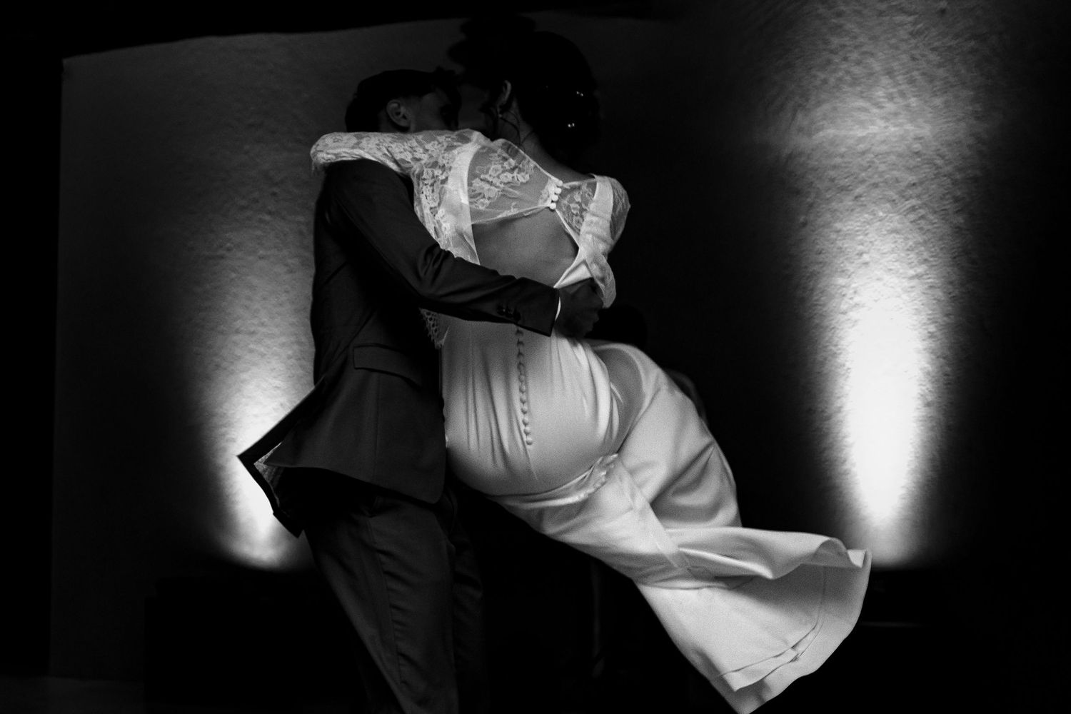 A dramatic black and white dance photo shows a couple in formal attire performing an elegant dip during a dance move.