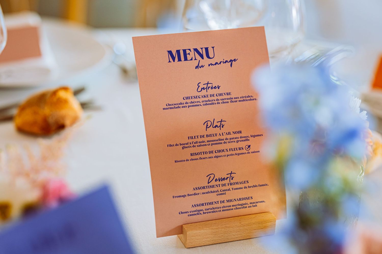 Wedding menu cards displayed in soft pink and navy blue colors with elegant typography at a reception table setting.