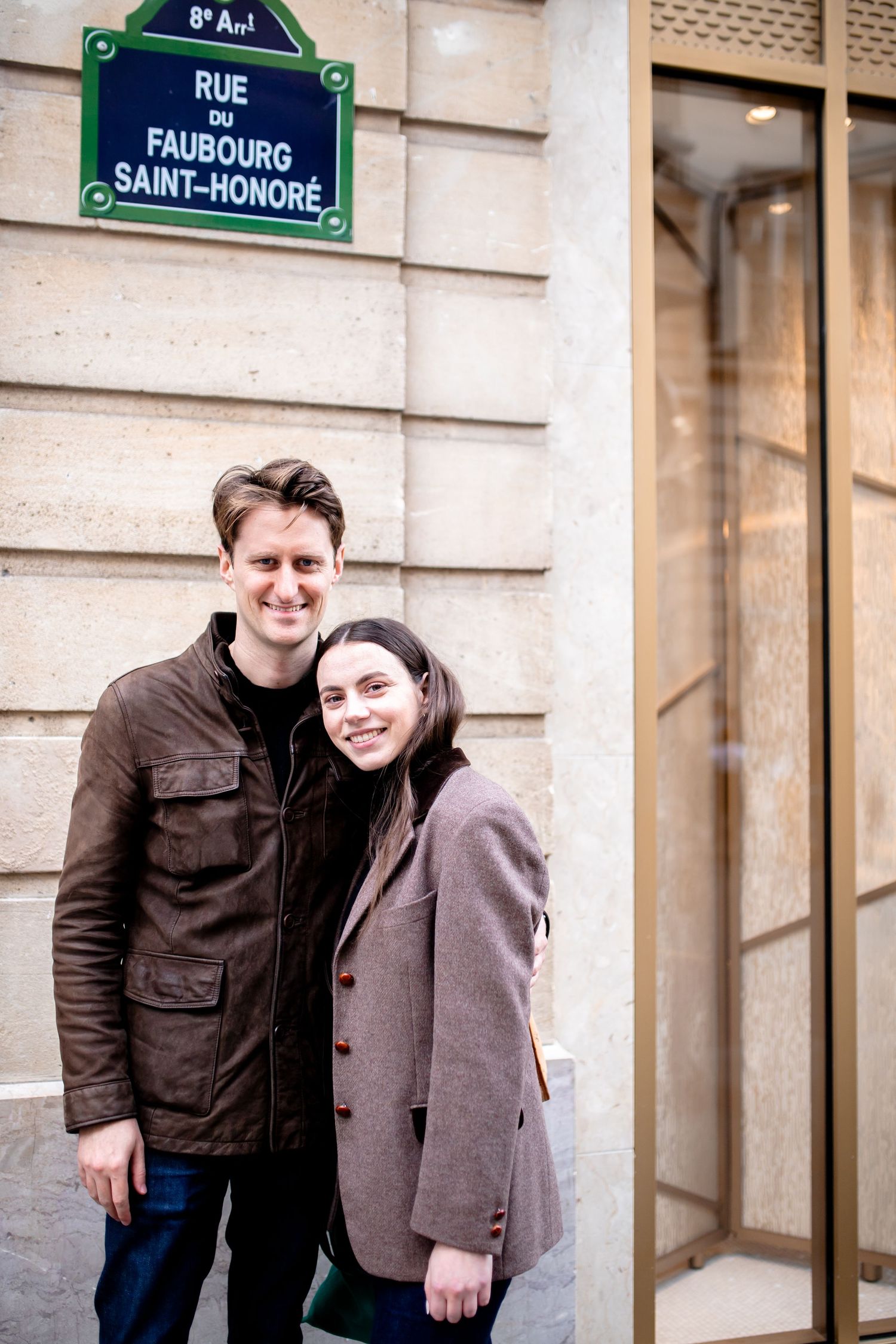 A couple poses together under a Rue Saint-Honore street sign in Paris.