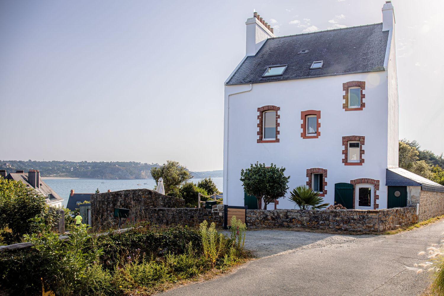A series of white coastal cottages with traditional stone architecture overlook a scenic seaside landscape in Brittany.