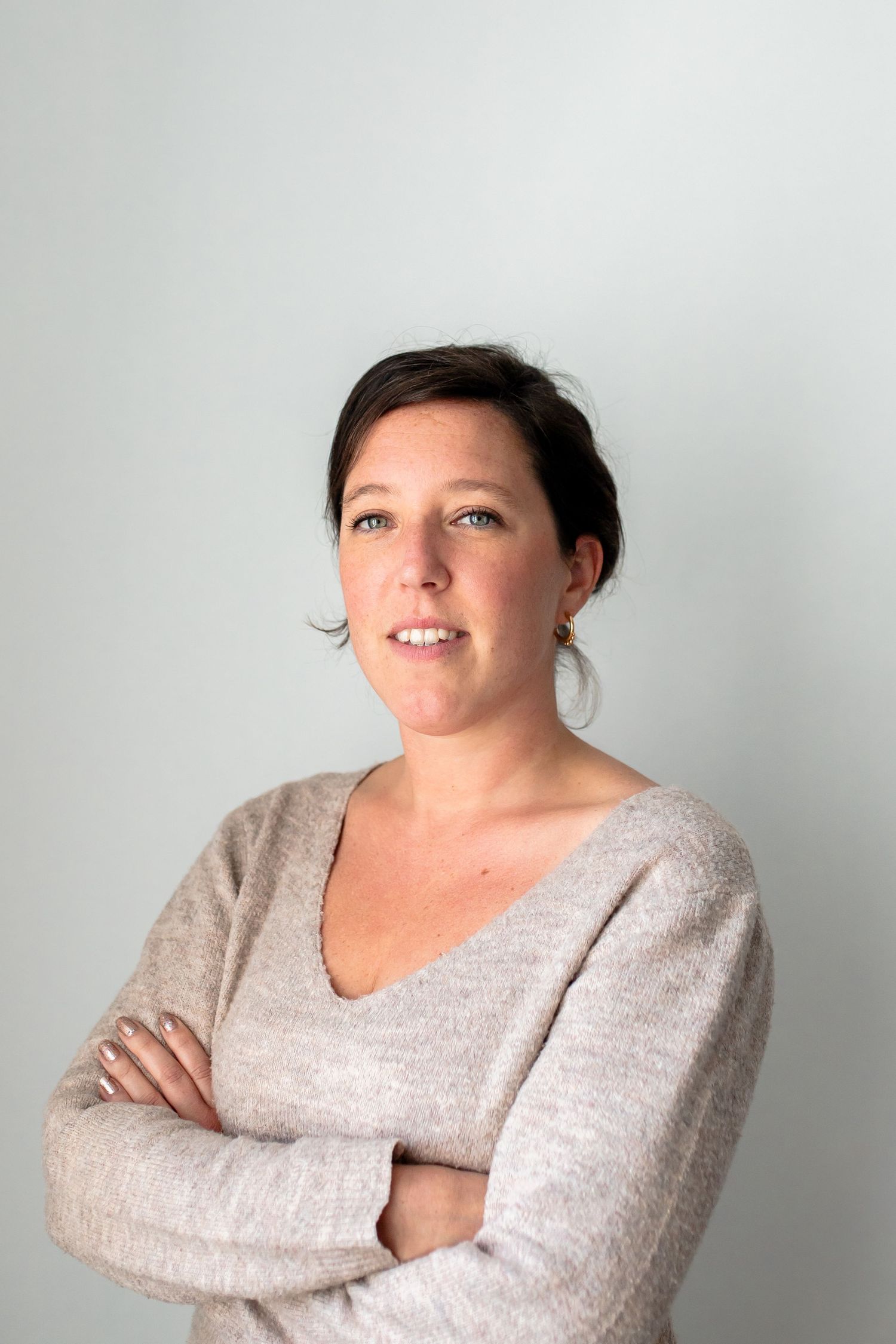 Portrait of someone in a beige sweater with short hair against a light background.
