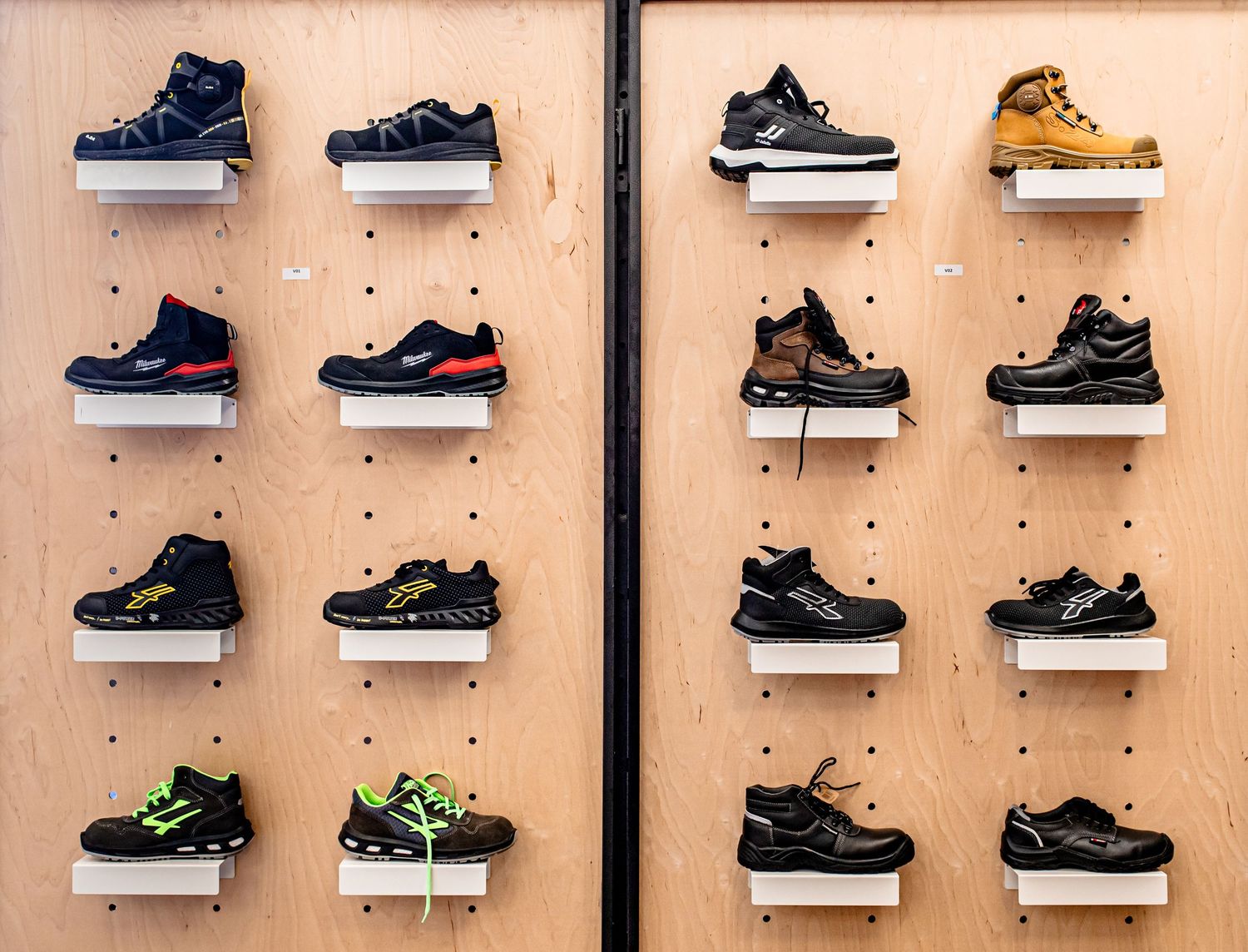 Display wall of athletic sneakers arranged on wooden pegboard shelving.