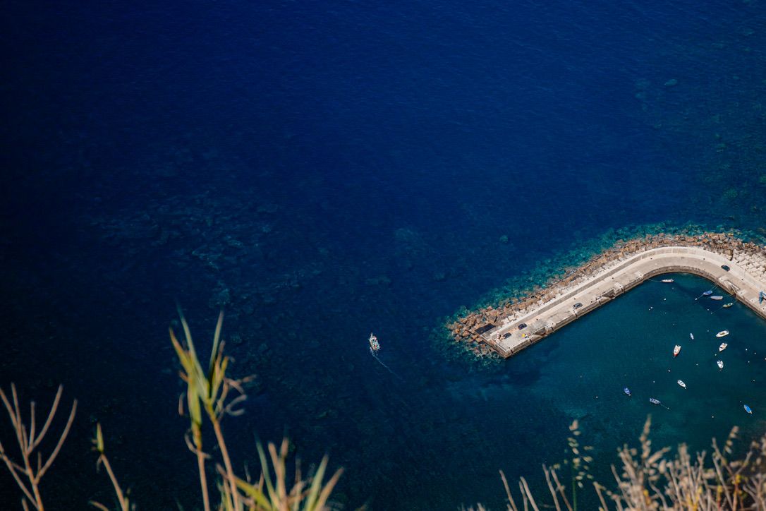 Aerial view of a breakwater extending into deep blue ocean waters.