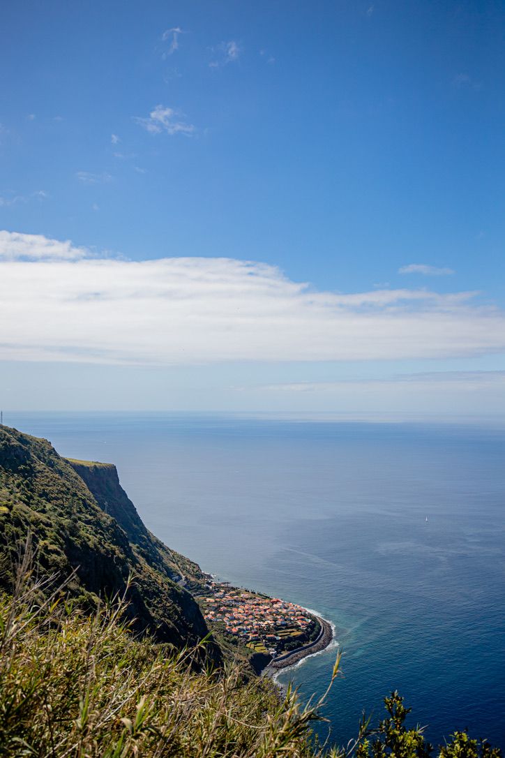 Panoramic coastal landscape view of a mountainous shoreline with blue ocean waters and clear skies.